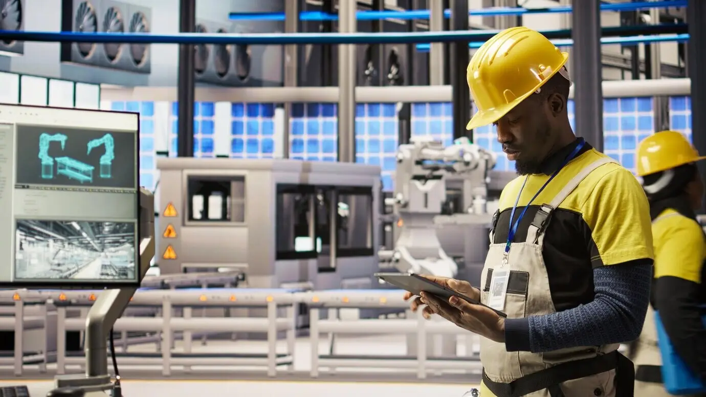 Mechaniker einer Smart Factory verwendet ein Tablet, um IoT-Sensordaten zu analysieren.